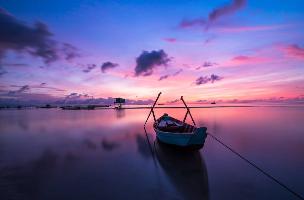 Mastering the First Impression: Your intriguing post title goes here A tranquil tropical sunrise with a lone boat on calm waters.